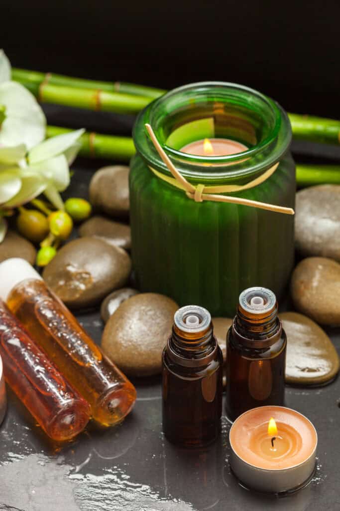 Aromatherapy candle with essential oils and stones for massage therapy.